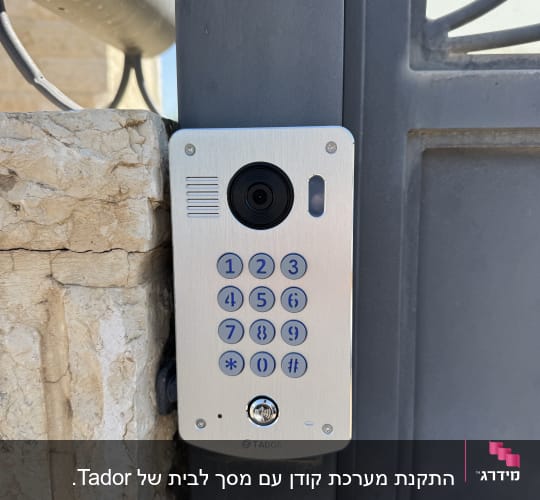 אינטרקום מותקן על קיר אבן ליד שער מתכת